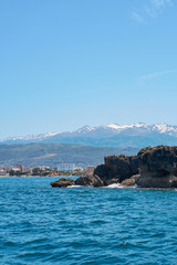 Fototapeta premium Sea coast with rocks in Chania, Crete, Greece with mountains and clear blue sky on a background.