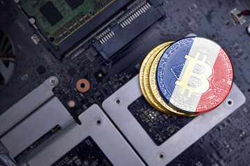 golden bitcoins with flag of france on a computer electronic circuit board. bitcoin mining concept.