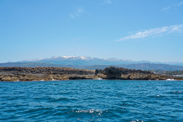  Sea coast with rocks in Chania, Crete, Greece with mountains and clear blue sky on a background.