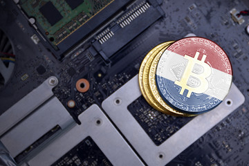 golden bitcoins with flag of netherlands on a computer electronic circuit board. bitcoin mining...