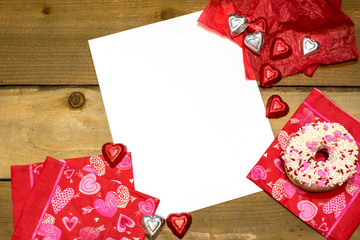 Paper on a Valentine's Day Background with chocolates and a doughnut on wood