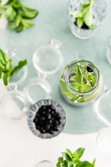 Top view Ingredients for infused water fresh mint leaves and black currant berries in a glass