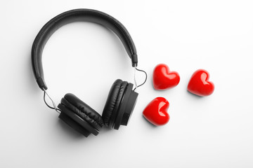 Decorative hearts and modern headphones on white background, top view