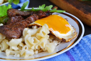 Steak of wild boar with egg and pasta. Home russian cuisine