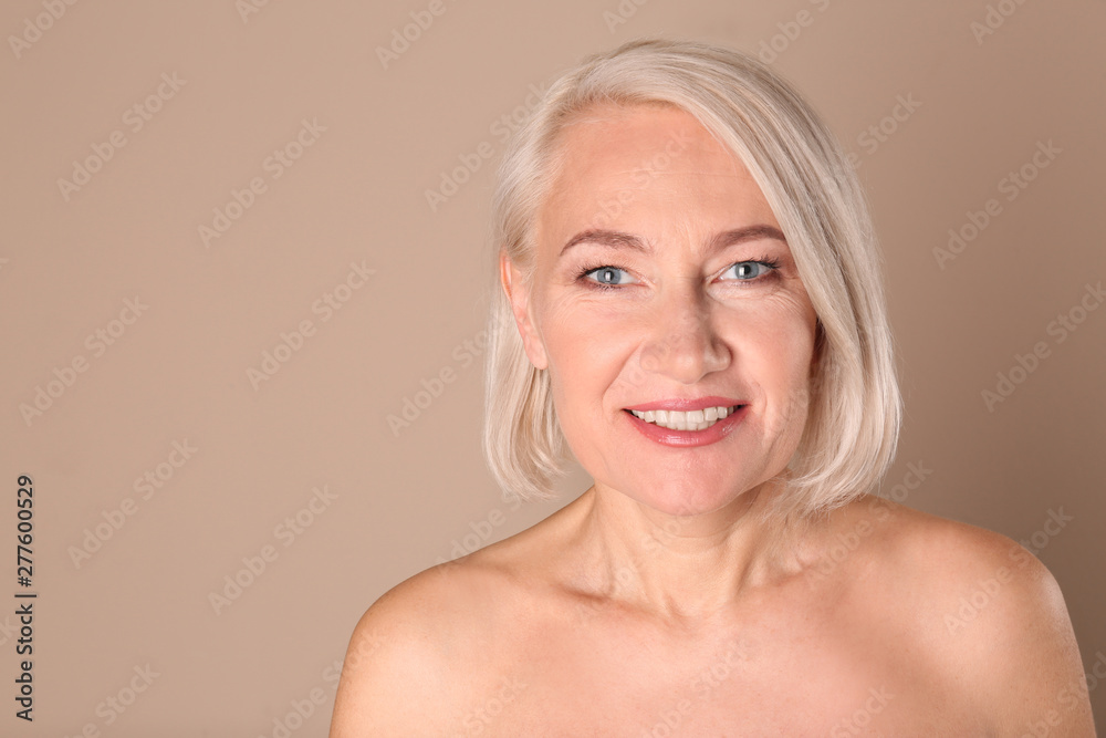 Poster Portrait of charming mature woman with healthy beautiful face skin and natural makeup on beige background, space for text