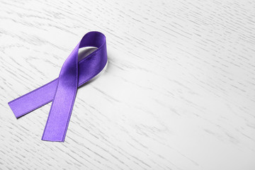Purple ribbon on white wooden background, space for text. Domestic violence awareness