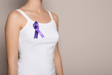 Woman wearing purple ribbon on grey background, closeup with space for text. Domestic violence...