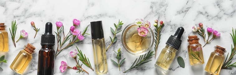 Flat lay composition with bottles of natural tea tree oil and space for text on white marble...
