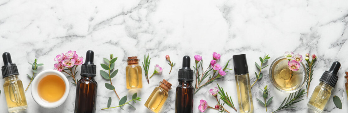 Flat lay composition with bottles of natural tea tree oil and space for text on white marble background