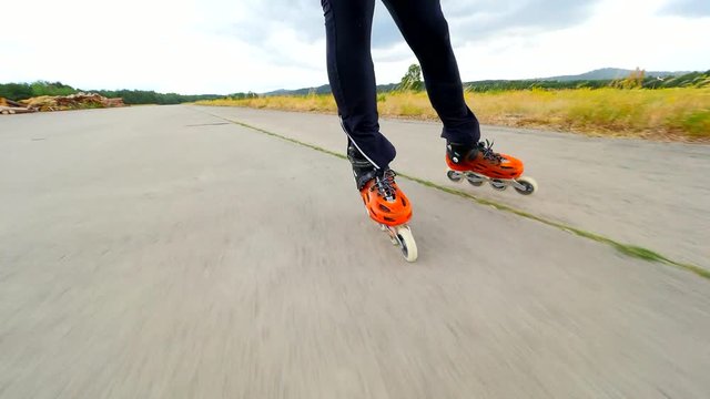 Roller skating in summer.  Hradcany airport, 9th of July 2019, Orange hard shell rollerskates on asphalt on sunny day. Inline skating out of the city. Fun free time activity. 