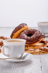Chocolate donuts and coffee on bright wooden background
