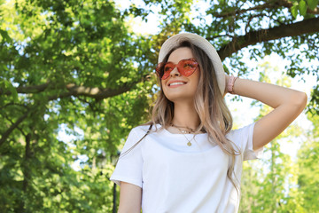 Portrait of happy woman with heart shaped glasses in summer park. Space for text