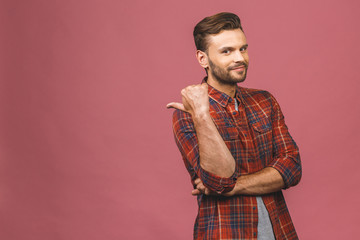 Handsome smiling bearded man pointing away on pink background.