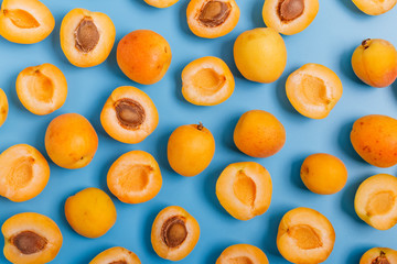 Apricots on a blue background. Whole and sliced apricots. Top view, flat lay.