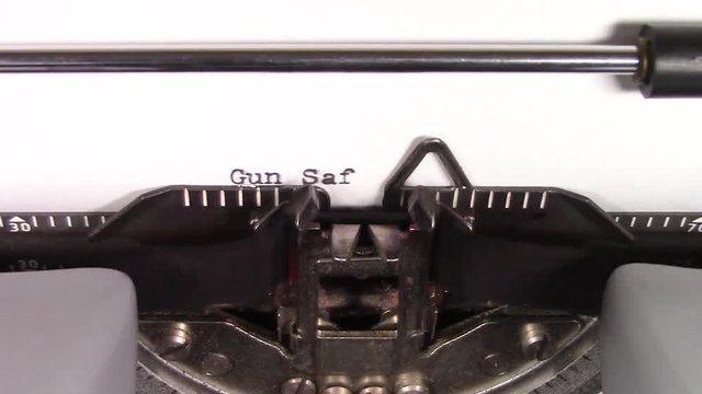 A close up video of the words "Gun Safety 101 " being typed on white paper in an old manual typewriter. Shot in macro.