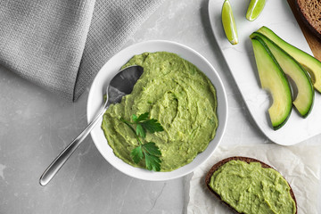 Flat lay composition with guacamole made of ripe avocados on light table