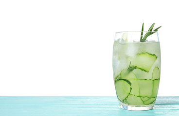 Glass of refreshing cucumber lemonade and rosemary on blue wooden table against white background. Summer drink