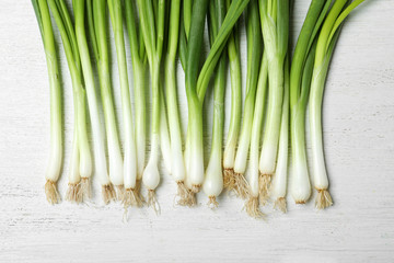 Fresh green onions on white wooden background, top view