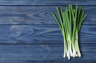 Fresh green onions and space for text on blue wooden background, top view