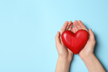 Woman holding heart on blue background, top view with space for text. Donation concept