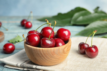 Wooden bowl with ripe sweet cherries on table