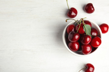 Bowl with sweet cherries on white wooden table, top view. Space for text - Powered by Adobe