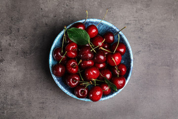 Bowl with delicious sweet cherries on grey table, top view
