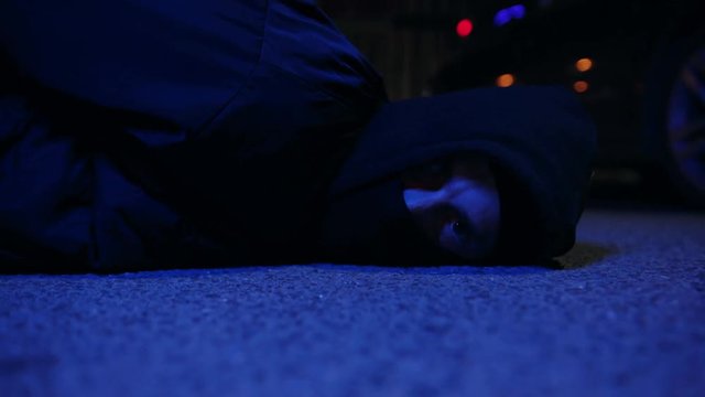 Face man ganster lying on ground police caught a bandit silen light in the dark at night police protection arrest balaclava crowbar dangerous defense handcuffs masked people person violence