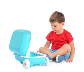 Fototapeta premium Cute little boy sitting with blue suitcase on white background