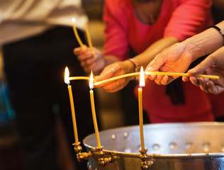 Close up somebody's hands set fire to a wax candle in the church