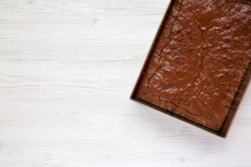 Homemade chocolate brownie on a white wooden background, overhead view. Top view, from above, flat lay. Copy space.