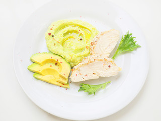 Healthy balanced lunch with baked chicken breast, avocado slices and mashed potato on white background, top view. 