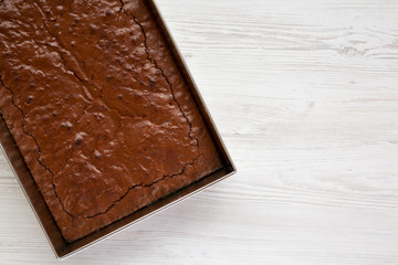 Homemade chocolate brownie on a white wooden background, top view. Overhead, from above, flat lay. Space for text.