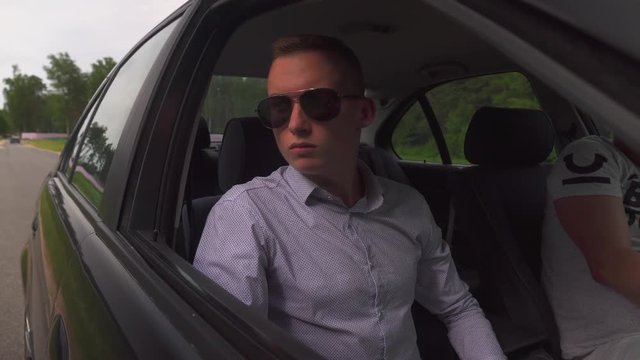 a young guy, a man in sunglasses, sits in the car and opens the window, lowers the side window.
