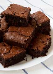 Freshly baked chocolate brownies on a white plate, side view. Closeup.