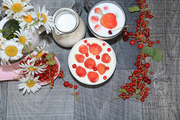 Strawberry yogurt, milk and ripe currant berries and strawberries on a light background, the concept of a healthy diet. Delicious healthy breakfast of yogurt and strawberries with copy space, top view