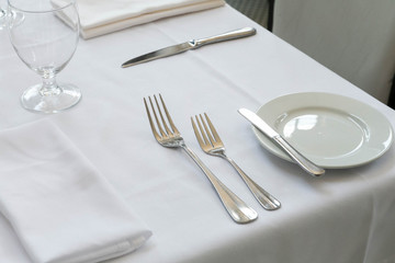 Table Setting at Fine Dining Restaurant, White Table with Plates, Silverware, and Napkin at Fancy Restaurant