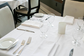 Table Setting at Fine Dining Restaurant, White Table with Plates, Silverware, and Napkin at Fancy Restaurant