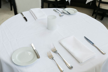 Table Setting at Fine Dining Restaurant, White Table with Plates, Silverware, and Napkin at Fancy Restaurant