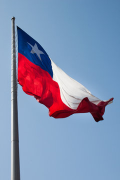 Chile Flag waving in the wind in front of La Moneda Palace. Chilean Independence day. International Travel. Red, White and blue flag with an star on a metal pole. Patriotism and culture Concept.