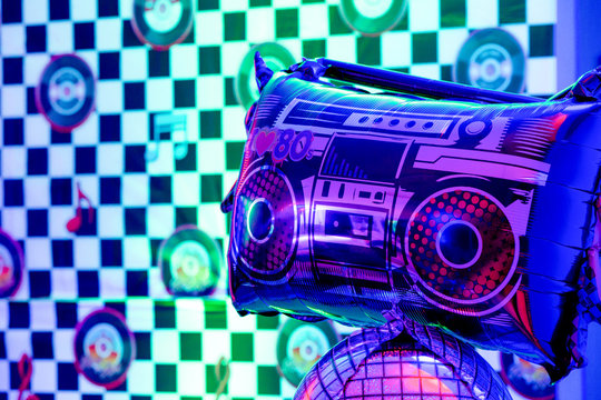 Eightees party decoration. Radio balloon closeup with a records checkered background. Concept 80s party time. - Powered by Adobe