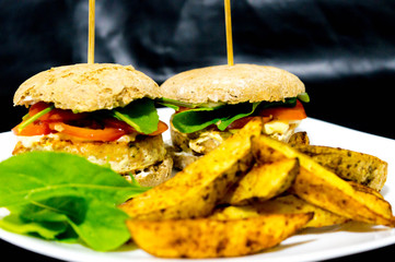  Salmon burger with rustic potatoes and rucula leaves.