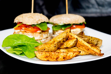  Salmon burger with rustic potatoes and rucula leaves.