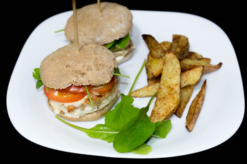  Salmon burger with rustic potatoes and rucula leaves.