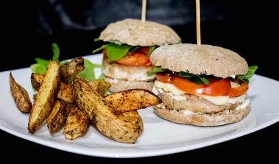  Salmon burger with rustic potatoes and rucula leaves.