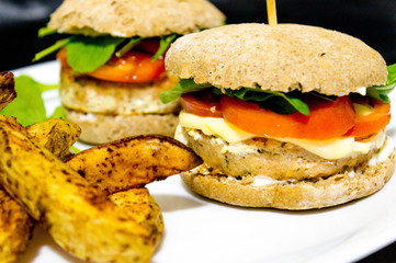  Salmon burger with rustic potatoes and rucula leaves.
