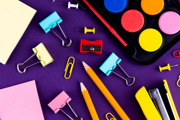 School office supplies stationery on a purple background desk. Back to school concept