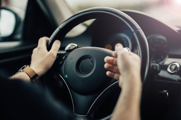 Naklejka premium driver's hands gesticulate behind the wheel of a car