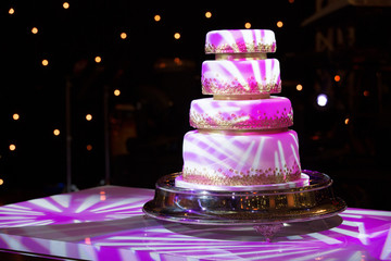 Beautiful isolated cake with party lights. Social event concept. Four-story cake for a birthday celebration or a wedding reception.