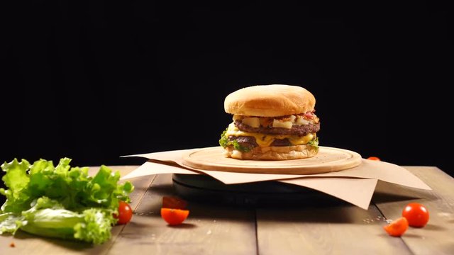 Fresh appetizing hamburger rotating on black background.